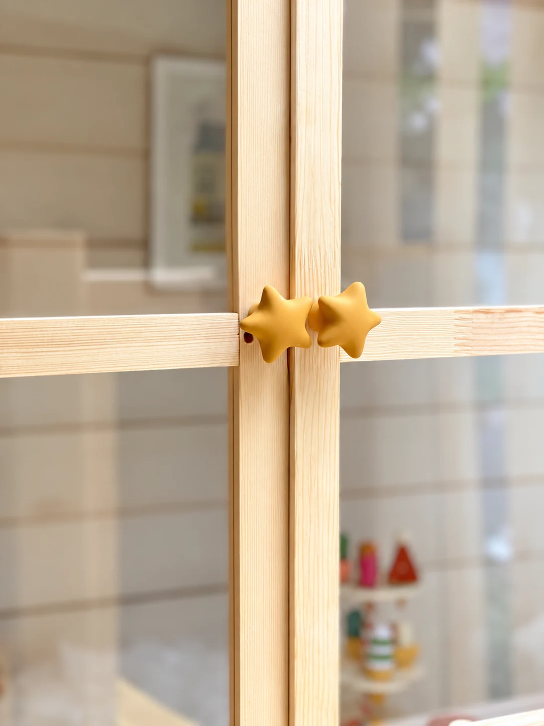 Close-up of yellow star-shaped knobs on the playhouse’s glazed timber doors