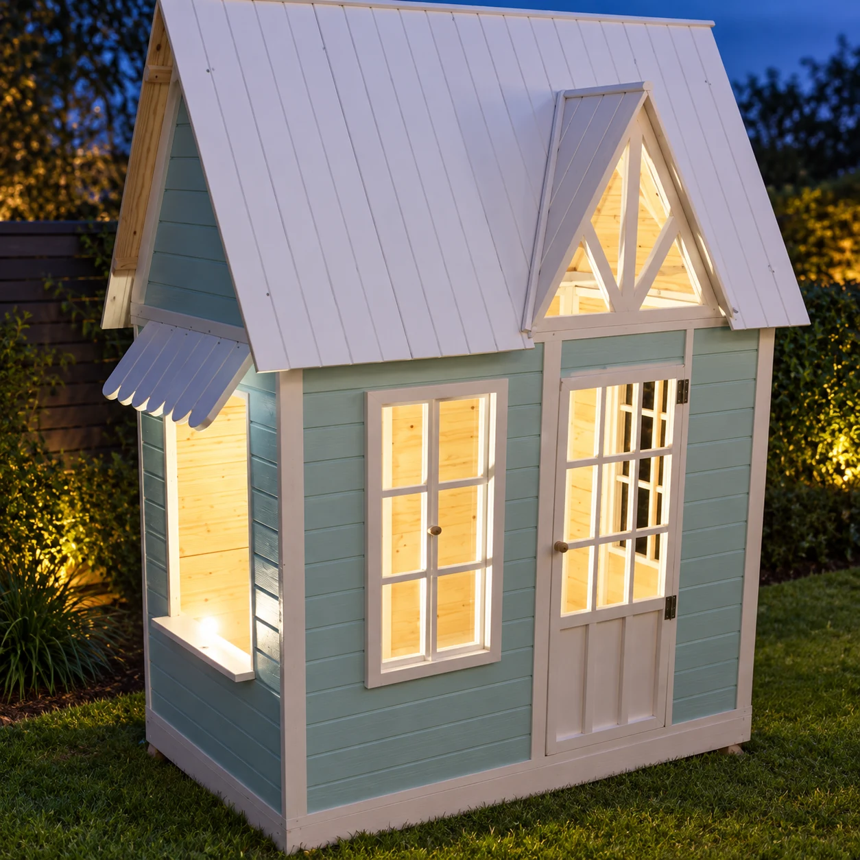 Blue-hour view of the playhouse with warm light shining through its windows