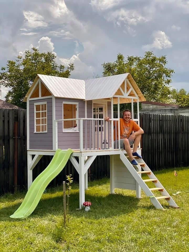 Original photograph of the lilac-grey playhouse with an adult seated on the steps